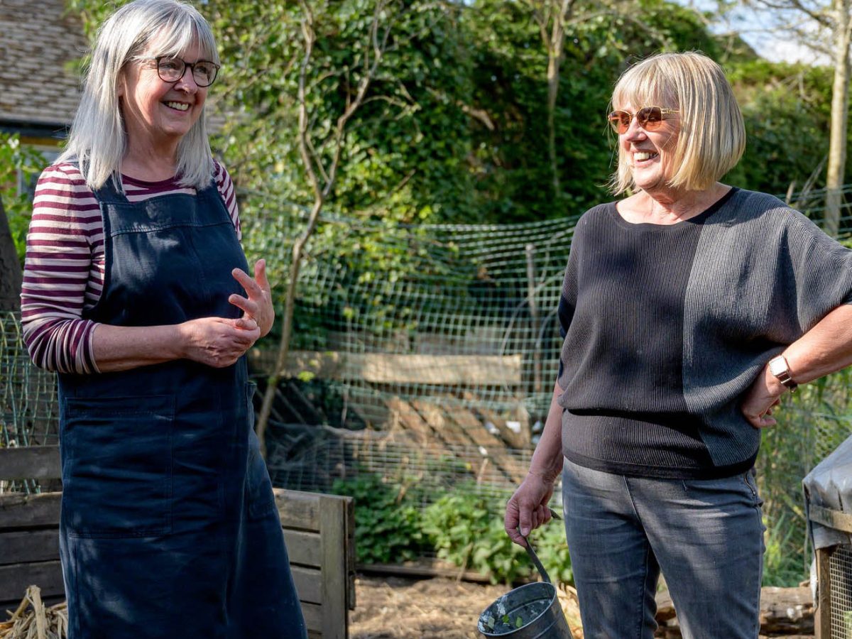 Two mature women smiling and talking outdoors, symbolizing the community Brownhill Homes fosters with their local roots and approachable service.