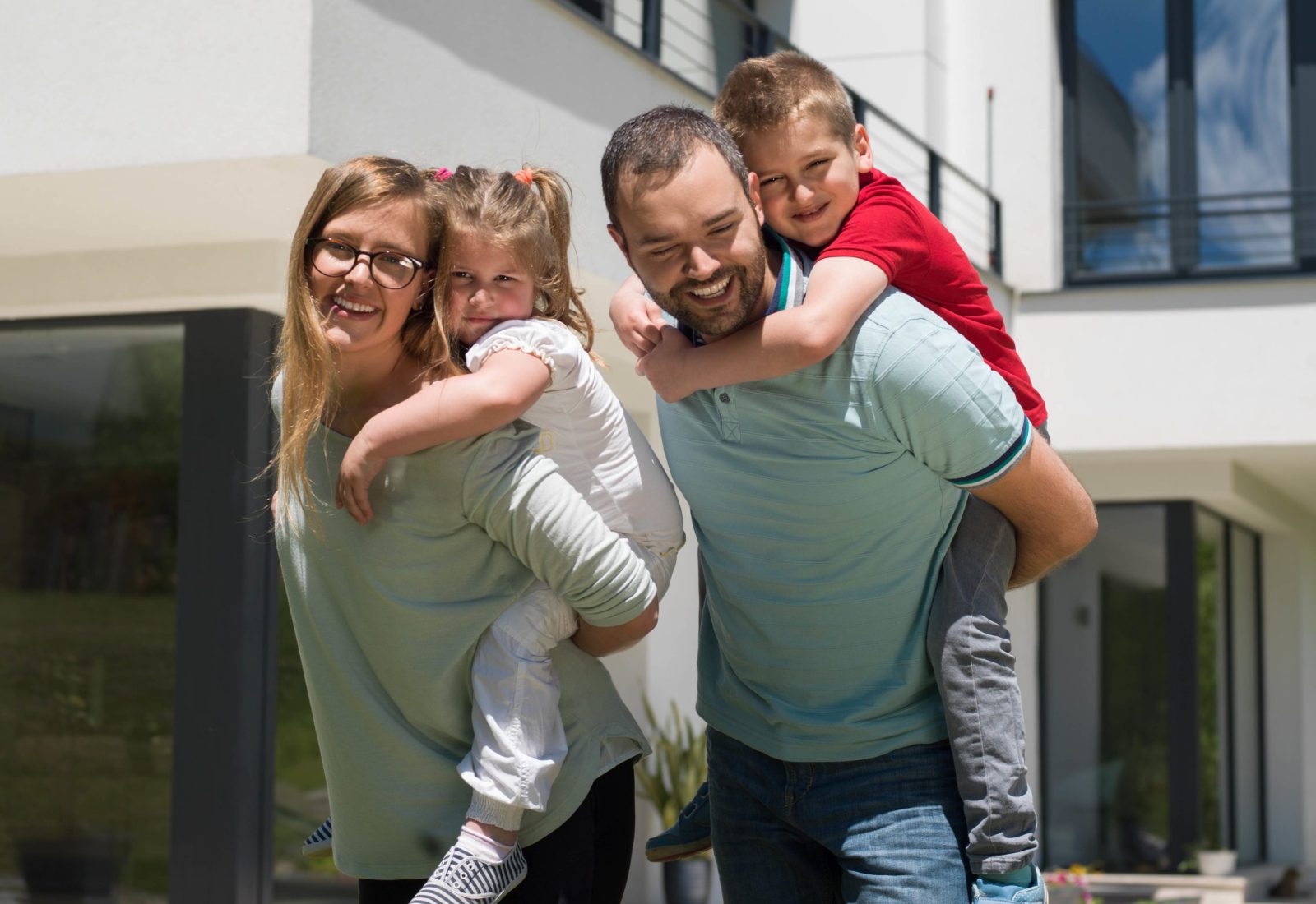 A family with two children smiling in front of their new home, illustrating the positive feedback Brownhill Homes receives from clients.